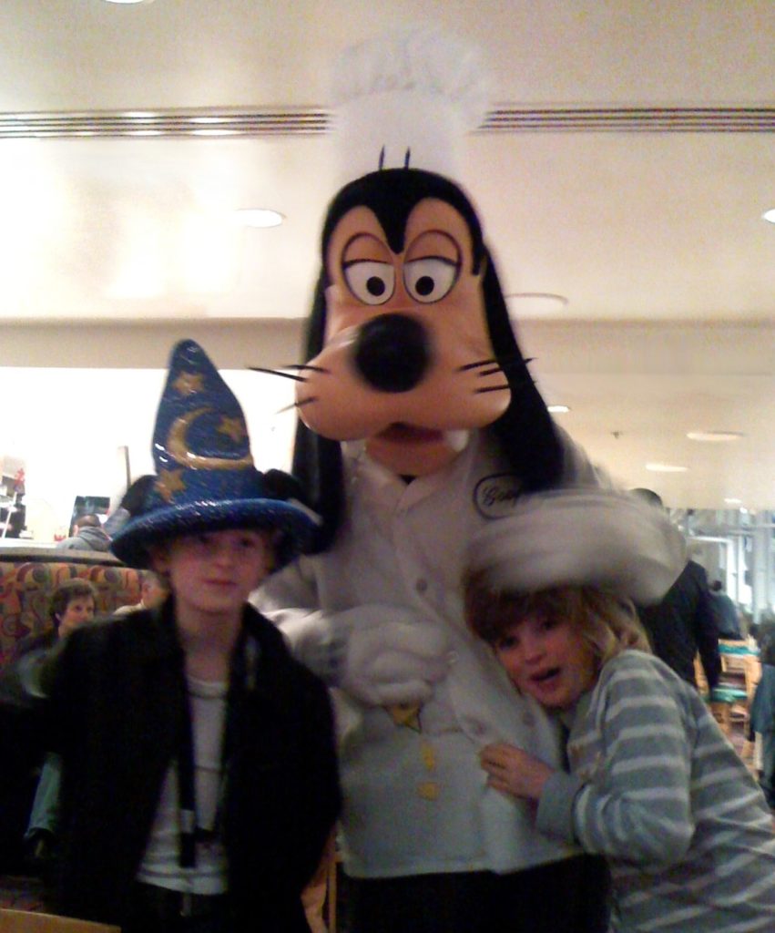 Two children take a picture with Goofy at Disneyworld