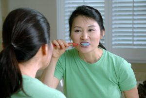 A woman brushing her teen in a mirror