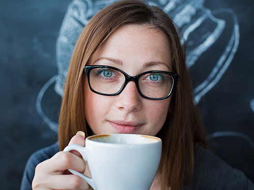 Woman drinking coffee & is unaware of the effects on dental health in Worcester & Central, MA.