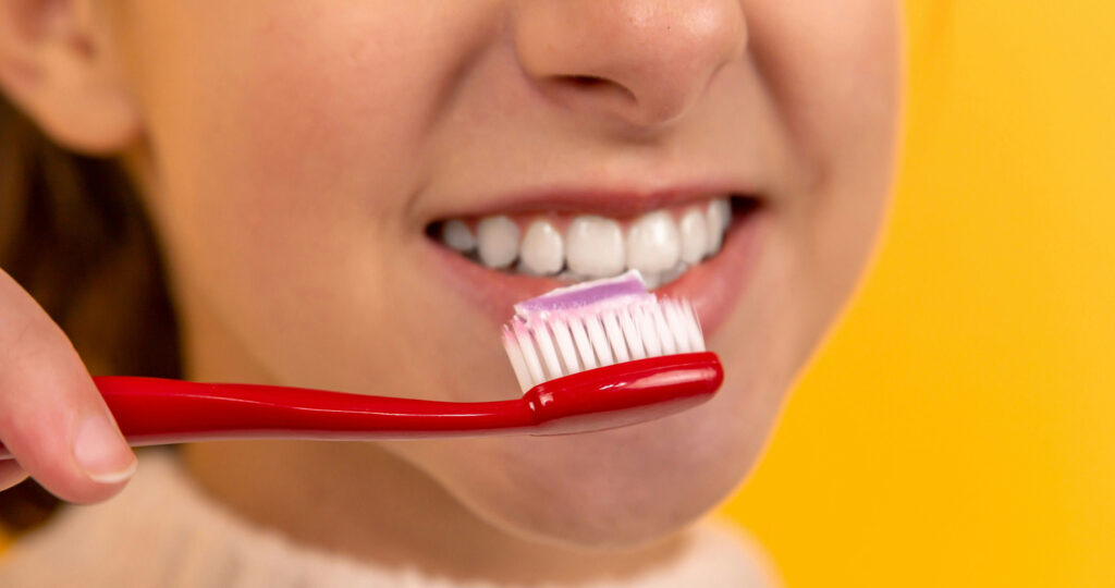 girl brushing her teeth smiling